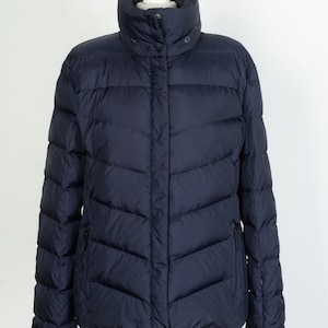 Peut inclure: Une veste matelassée bleu marine avec une fermeture éclair et un col montant.