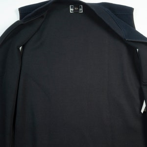 May include: A black fleece vest with a zipper closure. The vest is unzipped and laid flat, showing the inside lining.
