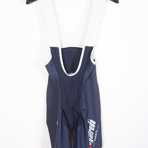 May include: Blue and white cycling bib shorts with white straps and the words "SANTINI" and "Syafredo Zanetti" printed on the legs.