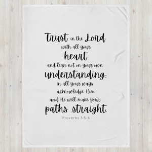 May include: White throw blanket with black text that reads "Trust in the Lord with all your heart and lean not on your own understanding: in all your ways acknowledge Him and He will make your paths straight. Proverbs 3:5-6"