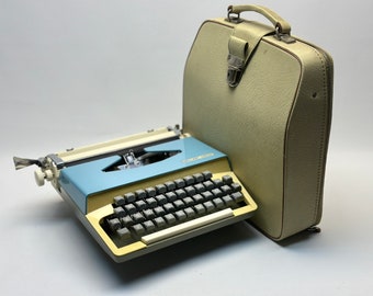 Briljante typemachine met blauwe omslag, gele accenten, roze typemachinelint, leren tas - antieke typemachine, volledig functioneel