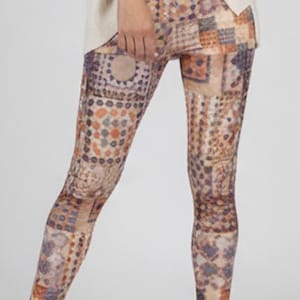 Può includere: Una donna indossa un top a maniche lunghe color crema e leggings fantasia. I leggings presentano un design a mosaico nei toni del marrone, arancione e viola. Indossa anche mocassini beige.