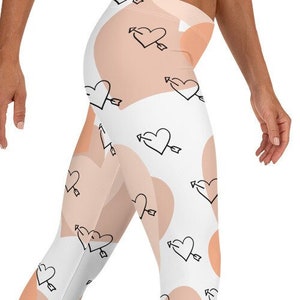 May include: White leggings with a pattern of peach-colored hearts with arrows through them.