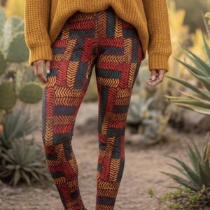 Könnte beinhalten: Eine Frau trägt einen senfgelben Pullover und gemusterte Leggings. Die Leggings haben ein geometrisches Design in Rot, Türkis und Gelb. Sie trägt braune Stiefeletten. Der Hintergrund ist eine verschwommene Außenszene mit Pflanzen.