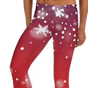 Pode incluir: Leggings compridas com um fundo de gradiente vermelho vibrante que escurece em direção à cintura. O tecido é decorado com um padrão repetitivo de flocos de neve brancos de vários tamanhos e pontos circulares brancos espalhados.