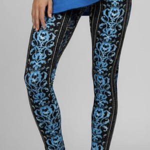 May include: Black leggings with a blue floral pattern and vertical black stripes. The leggings are paired with white sneakers and a blue top.