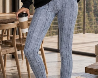 May include: A black long-sleeve pullover with a quarter-zip collar and a light blue pair of leggings featuring a vertical cable knit pattern. The outfit is completed with black and white athletic trainers with thick soles.