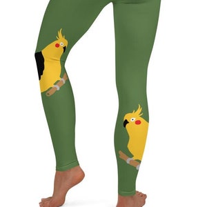 Puede incluir: Leggings verdes con un gráfico de pájaro amarillo y negro en cada pierna.