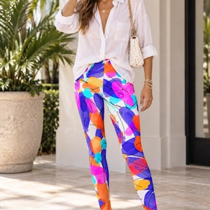 May include: High-waisted leggings featuring a vibrant abstract print with overlapping patches of bright orange, magenta, deep blue, and turquoise colours on a white background, accented by thin, scattered black ink-like scribbles and lines.