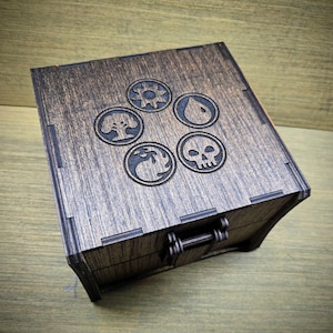 Scatola per carte ispirata a Magic the Gathering / Contiene 500 carte con bustina / Presenta una chiusura magnetica e include 2 dadi D20