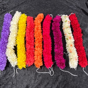 May include: A set of ten artificial flower garlands in various colors, including purple, white, yellow, orange, red, and pink. The garlands are made of fabric and are strung together with a white string.