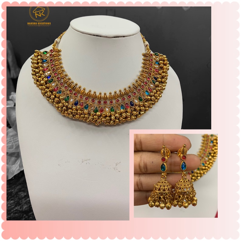 Op de afbeelding: Een gouden ketting met veelkleurige stenen en een bijpassend paar oorbellen. De ketting heeft een gelaagd ontwerp met kleine gouden balletjes en de oorbellen hebben een belvorm.