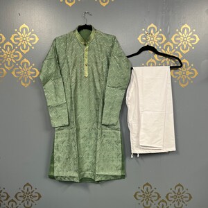 May include: A green kurta with white embroidery and a white pair of trousers. The kurta has a button-up collar and long sleeves.
