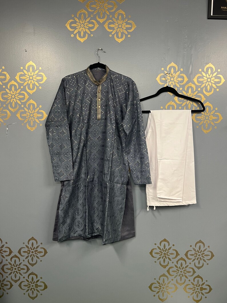 May include: A grey kurta with a white collar and silver embellishments, paired with white trousers. The kurta has a traditional Indian design and is hanging on a hanger.