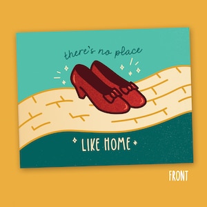May include: A green and yellow card with a pair of red ruby slippers on a yellow brick road. The card says "there's no place like home".