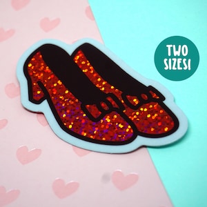 May include: Red glitter ruby slippers with black bows and a light blue outline. The sticker says "TWO SIZES!"