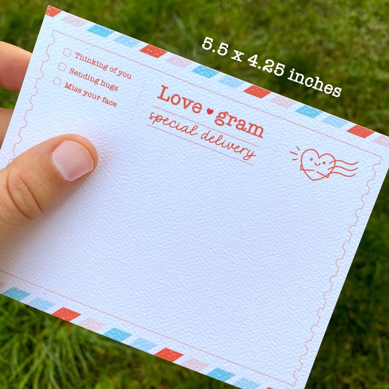 May include: A white card with a red and blue border. The card has a red heart with a smiley face and the text "Love gram special delivery". There are three checkboxes with the text "Thinking of you", "Sending hugs", and "Miss your face". The card measures 5.5 x 4.25 inches.