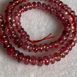 Puede incluir: Una hebra de cuentas de turmalina rosa, de aproximadamente 3 mm de tamaño, con un hilo rojo.