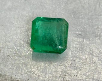 Puede incluir: Una gema de esmeralda verde vibrante con un corte cuadrado y un acabado pulido.