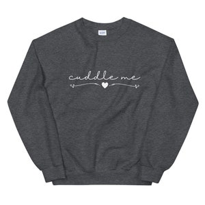 May include: A dark gray sweatshirt with the text "cuddle me" in white cursive lettering with a small heart symbol.