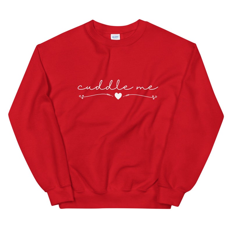 May include: Red sweatshirt with the text "cuddle me" in white cursive lettering with a small white heart in the middle.