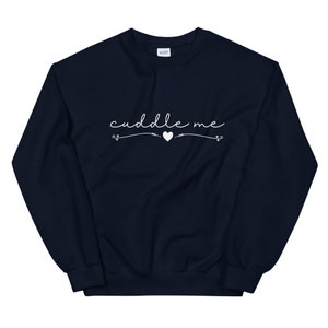 May include: A navy blue sweatshirt with the text "cuddle me" in white cursive lettering with a small white heart in the middle.