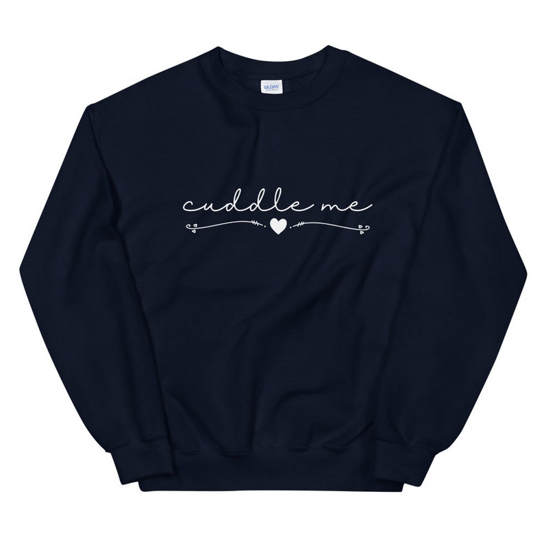May include: A navy blue sweatshirt with the text "cuddle me" in white cursive lettering with a small white heart in the middle.
