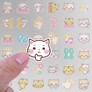 May include: A white cat sticker with a pink blush and a thoughtful expression. The sticker is surrounded by other cat stickers with various expressions and designs.