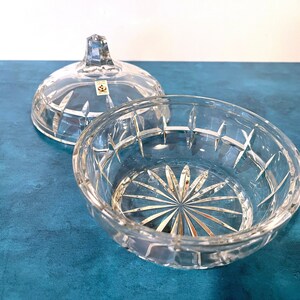May include: A clear glass bowl with a lid, both with a cut-glass design. The bowl has a starburst pattern at the bottom.