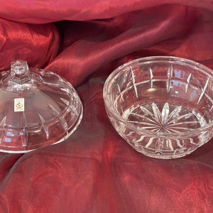 May include: A clear glass bowl with a lid, both featuring a cut-glass design. The bowl is round and has a wide opening. The lid has a knob on top.
