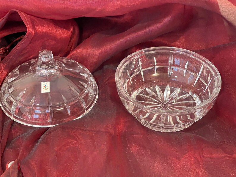 May include: A clear glass bowl with a lid, both featuring a cut-glass design. The bowl is round and has a wide opening. The lid has a knob on top.
