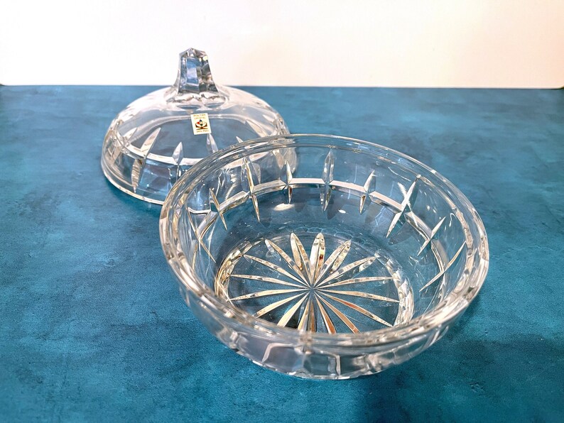 May include: A clear glass bowl with a lid, both with a cut-glass design. The bowl has a starburst pattern at the bottom.