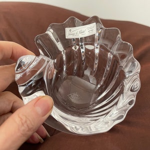 May include: A clear glass dish with a scalloped edge and a swirl design. The dish has a label that reads "Villeroy & Boch" and "Austria".