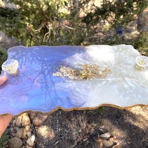 May include: A white and purple resin serving tray with gold leaf accents and clear glass handles. The tray has an irregular, organic shape.