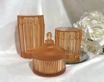 May include: Three amber glass containers with ribbed designs. The containers are different sizes and shapes, with one having a lid.