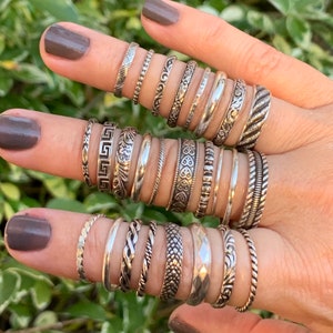 925 Sterling silver stacking rings in many sizes on a models hand. Cute dainty rings, midi, custom sizes, rings set, stackable real .925 silver. Patterns include leaves, vines, greek, hearts, twist, braded, snake, dots, place shiny silver, and more.