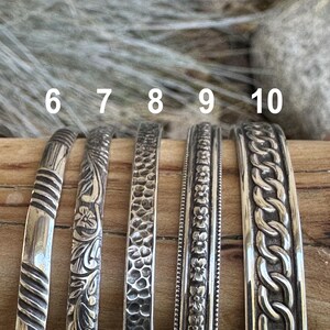 May include: Five silver bracelets with different designs. The bracelets are numbered 6 through 10.