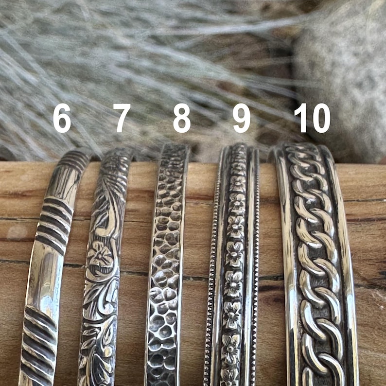 May include: Five silver bracelets with different designs. The bracelets are numbered 6 through 10.