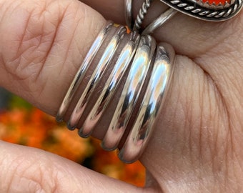May include: A set of six silver stacking rings. The rings are smooth and polished, and they are stacked on a finger.