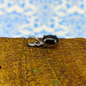 May include: A silver pendant with a black oval gemstone set in a silver bezel.