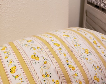 May include: A yellow and white striped pillow with a floral pattern. The pillow has a delicate floral design with small yellow flowers and green leaves.