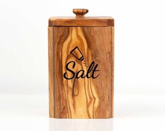 May include: Wooden salt container with a lid and the word "Salt" engraved on the front. The container has a natural wood grain pattern.