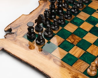 May include: A wooden chess set with black pieces arranged on a board. The board features a natural wood grain with green squares. The chess pieces are black and the board has a live edge design.