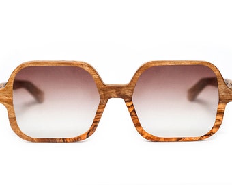 May include: A pair of brown wood-framed sunglasses with gradient brown lenses.
