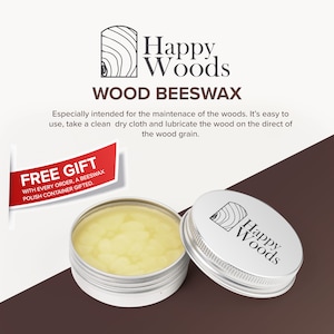 May include: A silver tin with a yellow beeswax polish inside. The tin has a wood grain logo that says "Happy Woods" on the lid. The text "WOOD BEESWAX" is printed in black on a white background. The text "FREE GIFT" is printed in red on a white background. The text "WITH EVERY ORDER, A BEESWAX POLISH CONTAINER GIFTED." is printed in black on a white background.