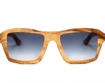 May include: A pair of wooden sunglasses with a gradient blue lens. The sunglasses have a unique, natural wood grain pattern.