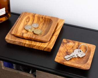 May include: Two square wooden bowls, one nested inside the other, with a few coins in the smaller bowl. A third square wooden bowl sits on a black surface with a set of keys inside.