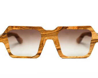 May include: A pair of brown wood-framed sunglasses with gradient lenses. The sunglasses have a unique, geometric shape.