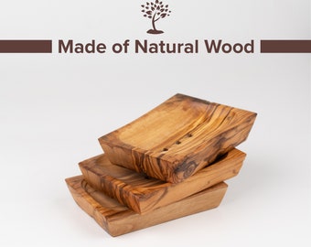 Puede incluir: Tres jaboneras de madera apiladas, hechas de madera natural. Las jaboneras son rectangulares y tienen una forma ligeramente curvada. La madera tiene una veta natural y un color marrón claro.