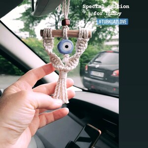 May include: A white macrame car charm with a blue evil eye bead and a wooden dowel. The charm is hanging from the rearview mirror of a car. The text "Special edition for hubby #TURKUA7LOVE" is visible in the image.